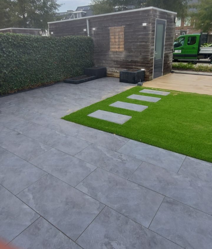 Opgeleverde tuin met terras, kunstgras met stapstenen en een zwart tuinhuis